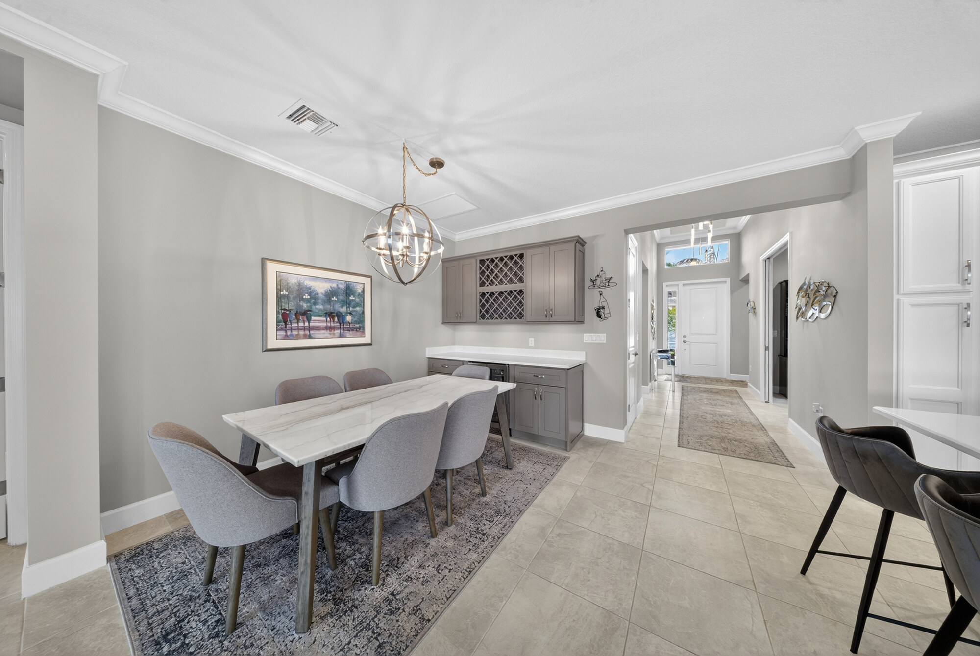 Dining area with a table for six under a globe chandelier, beside a built-in buffet and wine rack.