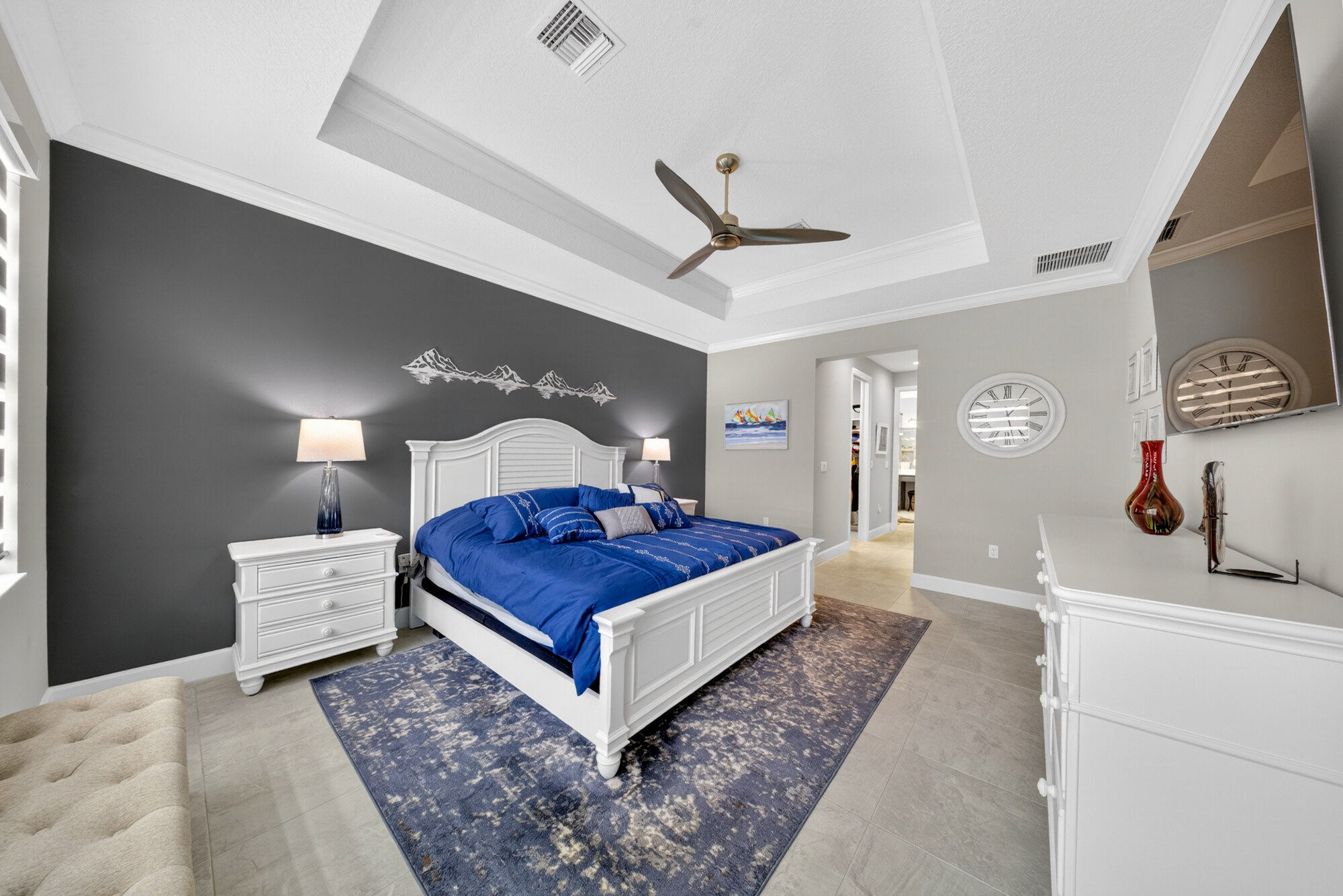 Primary bedroom with a tray ceiling and dark accent wall, furnished with a king bed and matching nightstands.