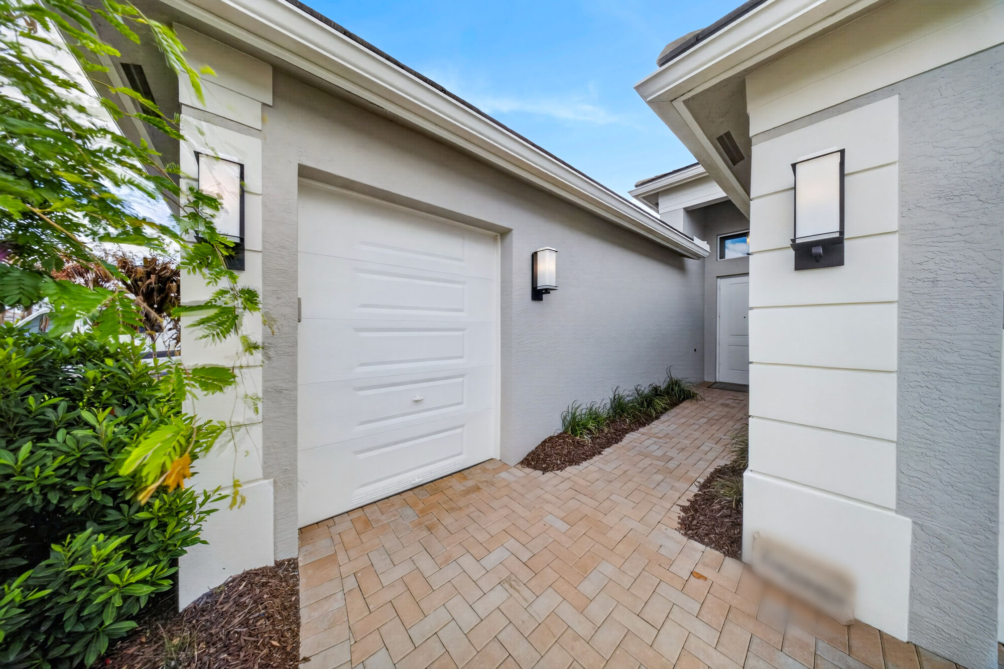 Exterior view of the separate golf cart bay door, beside the paver walkway leading to the front entry.