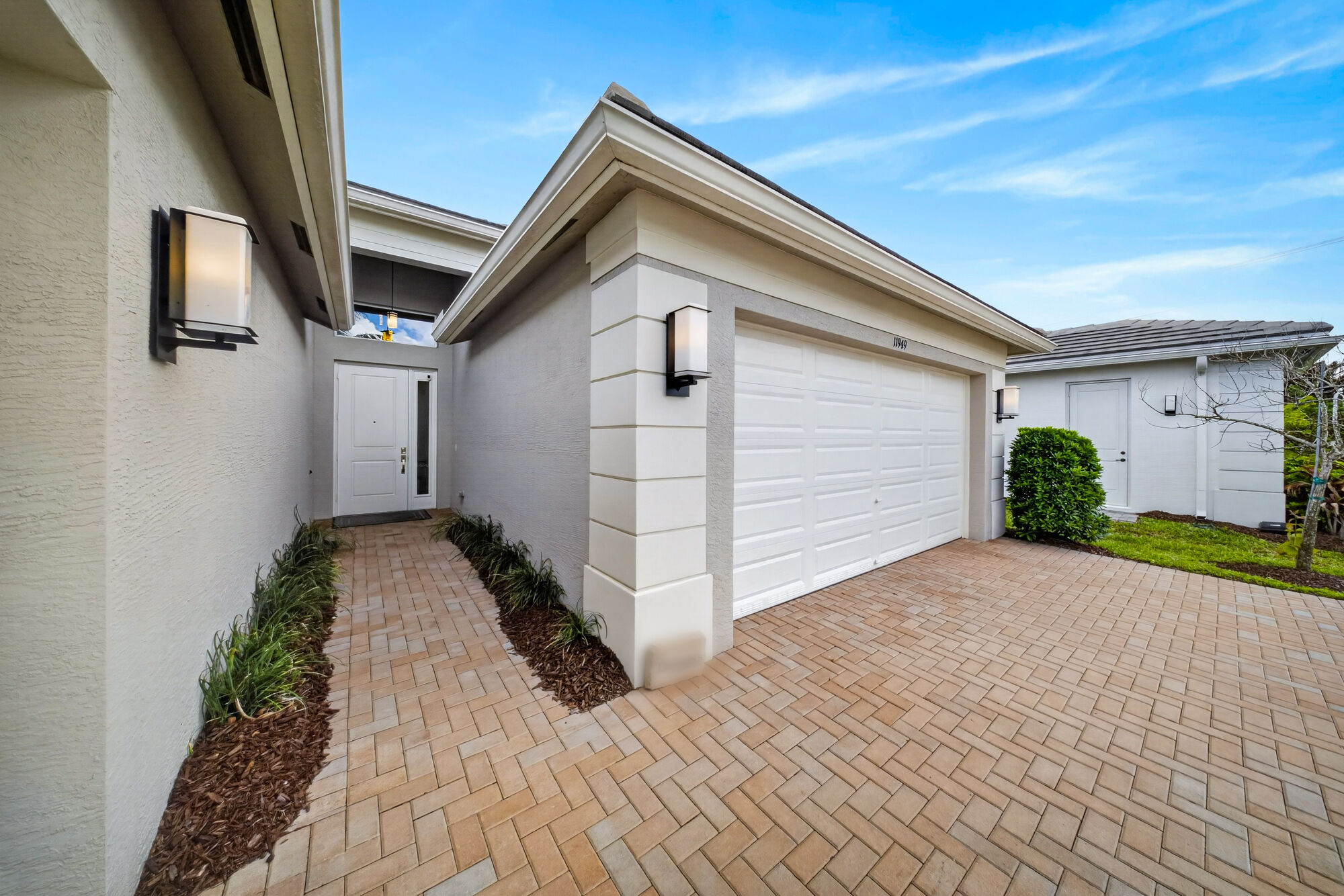 Front of the home from the driveway, showing the two-car garage door and the covered entry courtyard.